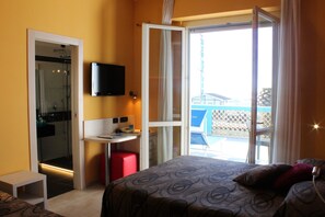 A hotel room with a bed, a desk, a shower, and a balcony with a view. - Hotel Eco del Mare (Massa)