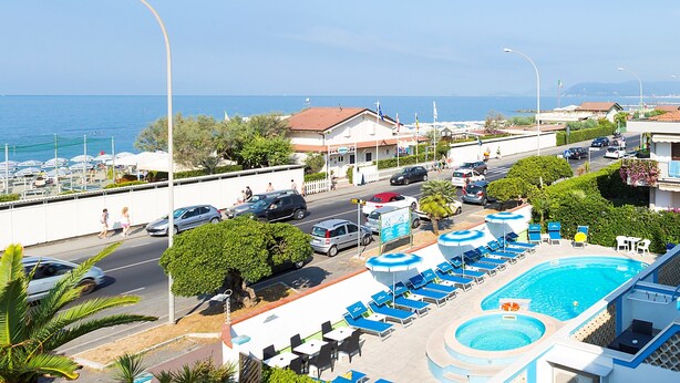 A resort with a swimming pool, lounge chairs, and a view of the sea. - Hotel Eco del Mare (Massa)