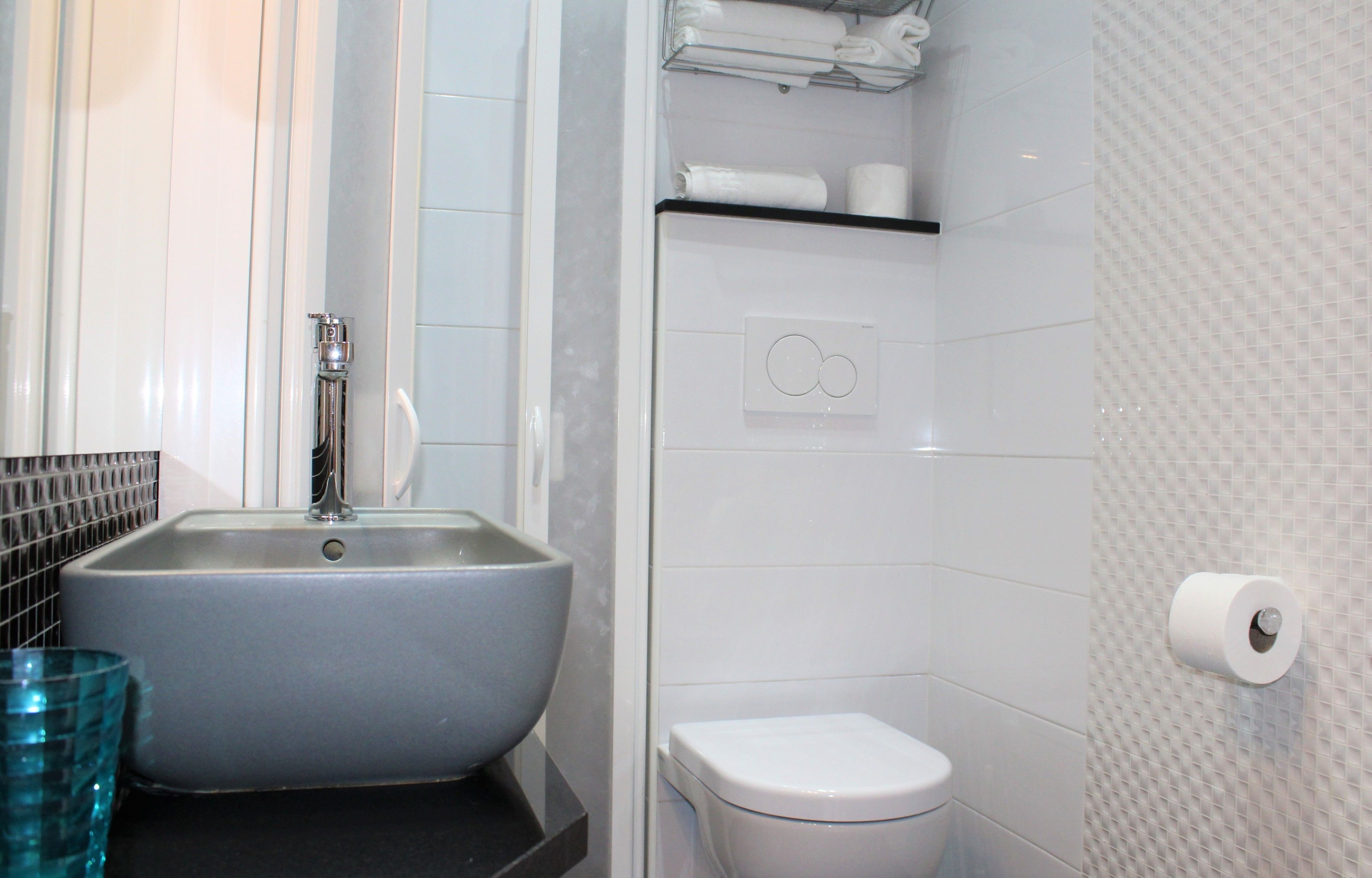 A bathroom with a large sink, toilet, and a towel rack.