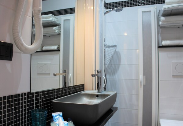 Un baño con lavamanos, espejo y ducha.