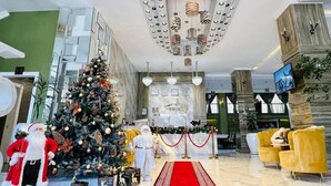 Een ontvangsthal met een kerstboom, een rood tapijt en een receptiebalie.