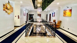 Een hotel lobby met een centrale trap, decoratieve leuningen en kunstwerken aan de muren.