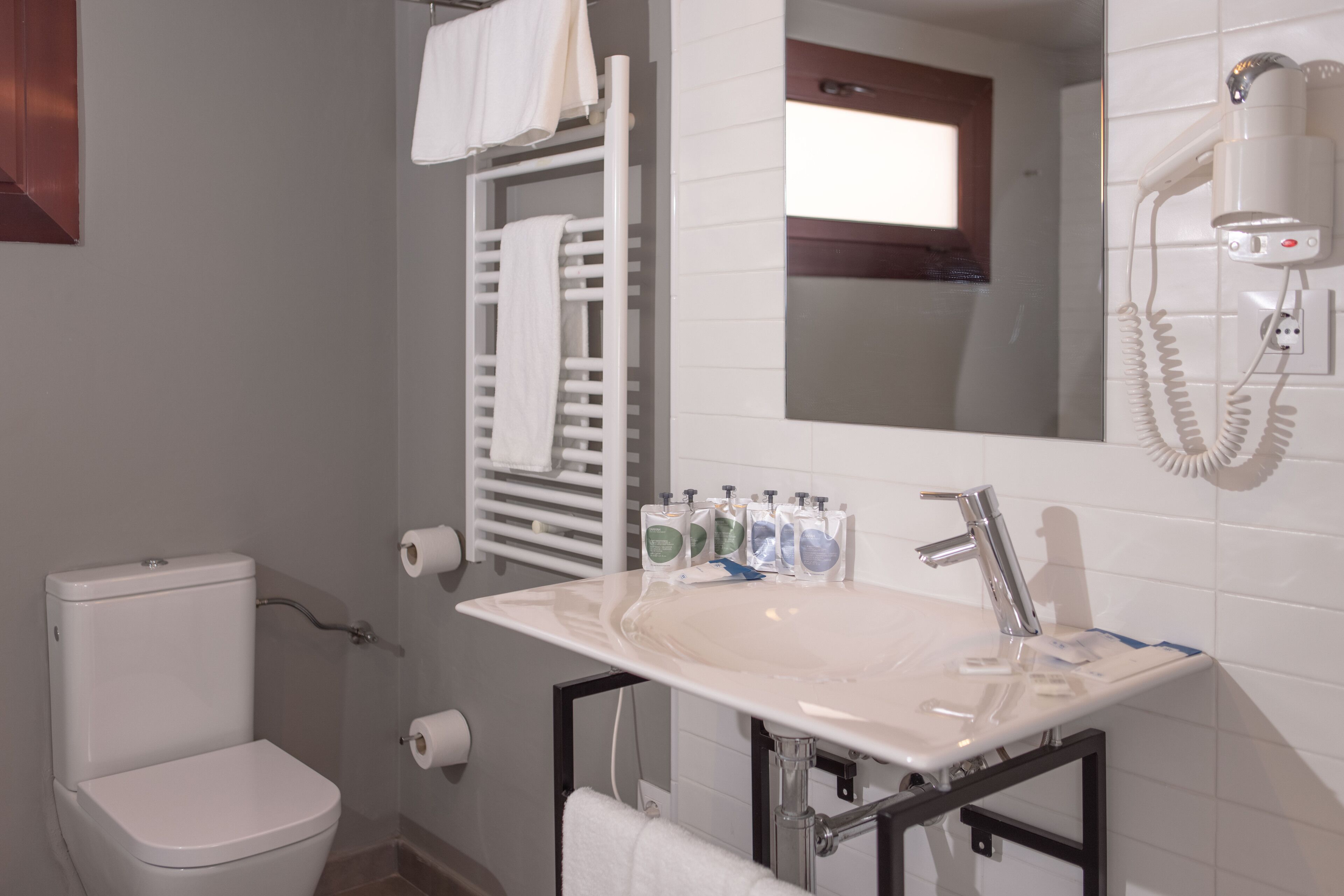 Een badkamer met een wit wastafel, toilet en handdoekhouder.