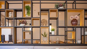 A modern dining area with multiple tables and chairs, a decorative wall with various plants and vases, and a warm lighting ambiance. - RVHotels Broquetas Spa Termal (Caldes de Montbui)