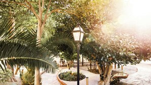 A garden pathway with a lamp post, surrounded by various plants and trees. - RVHotels Broquetas Spa Termal (Caldes de Montbui)