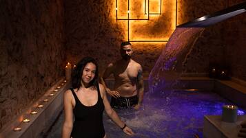 Zona de spa con fuente de agua, velas y lámpara con diseño geométrico.