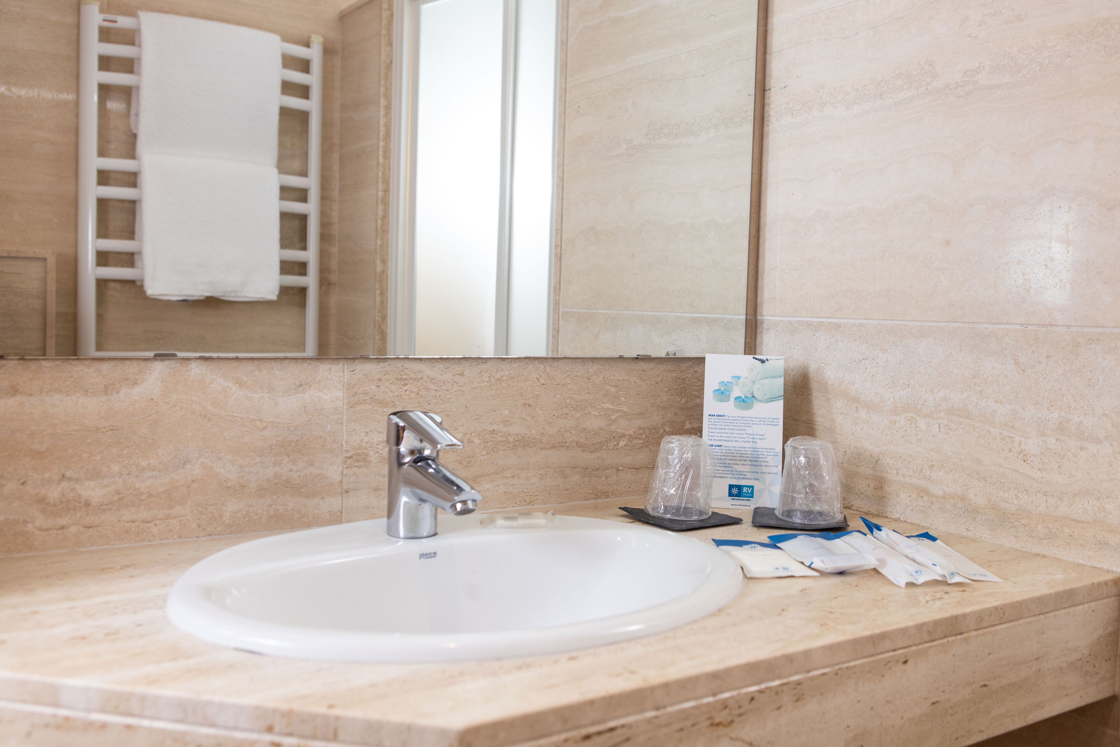 A bathroom with a white sink, a mirror, and a towel rack.