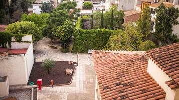 A courtyard with a tiled roof, a small garden area, and a red mailbox.