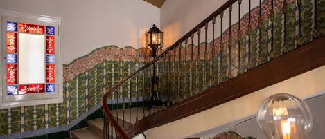 Una escalera con barandales ornamentados y una pared decorativa con motivos florales.