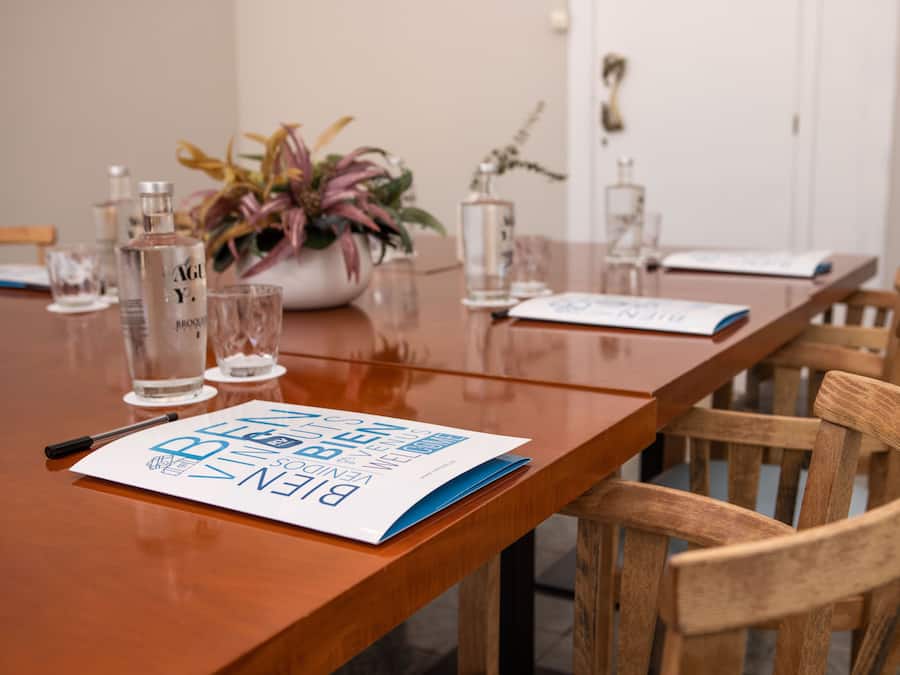 Una mesa de conferencias con un folleto, un bolígrafo y una planta en maceta.