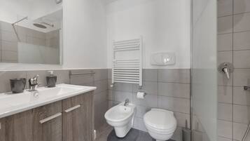 Un baño moderno con ducha, bidé, inodoro y tocador con espejo y lavamanos.