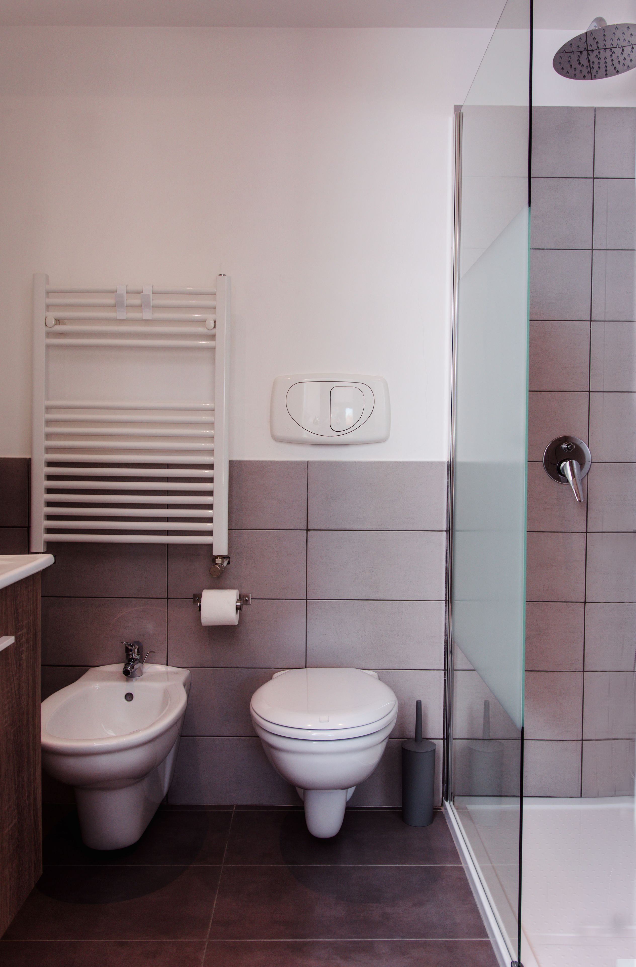 A modern bathroom with a bidet, toilet, and glass shower enclosure.