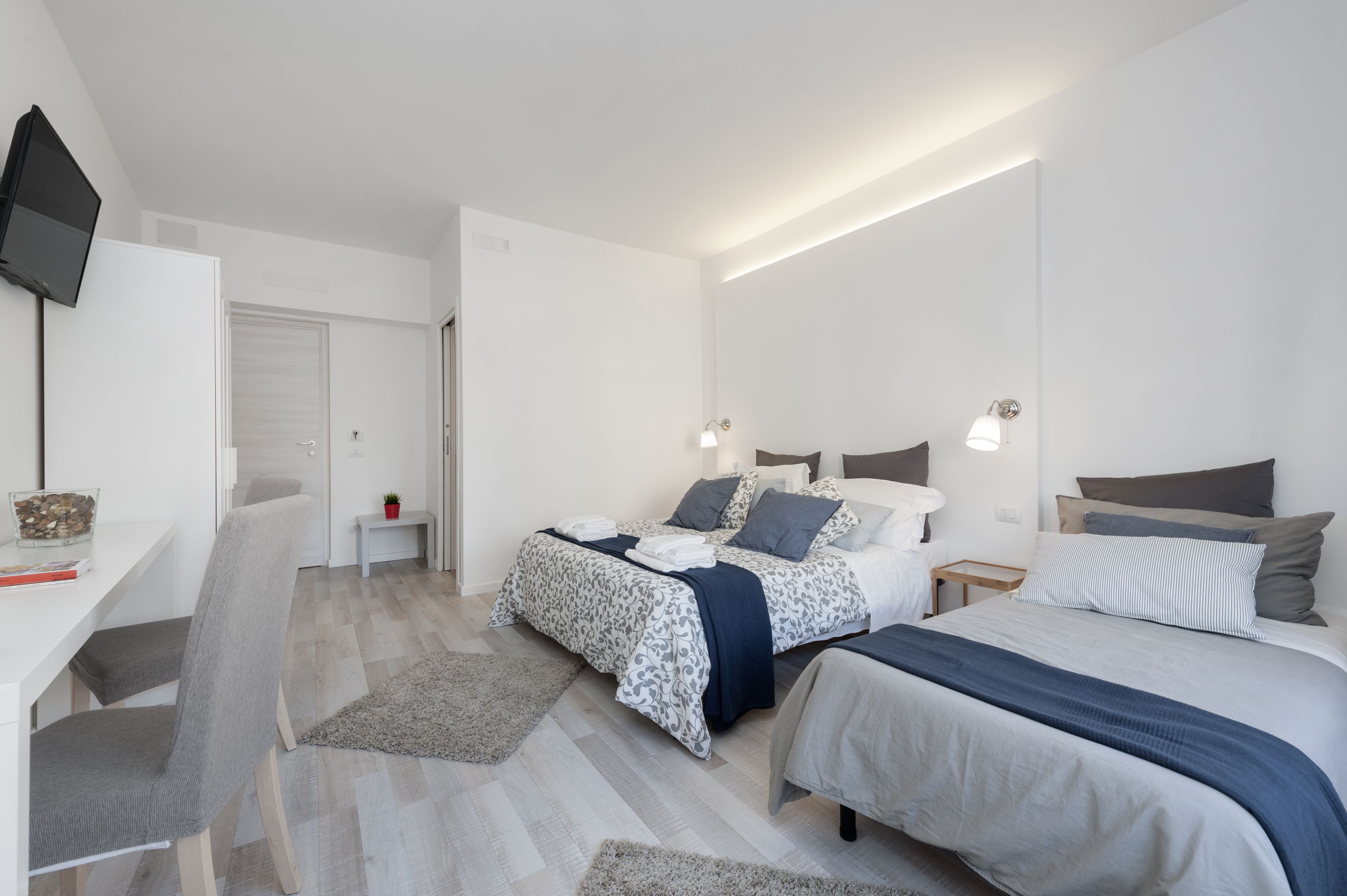 Een moderne slaapkamer met twee bedden, een bureau en een televisie.