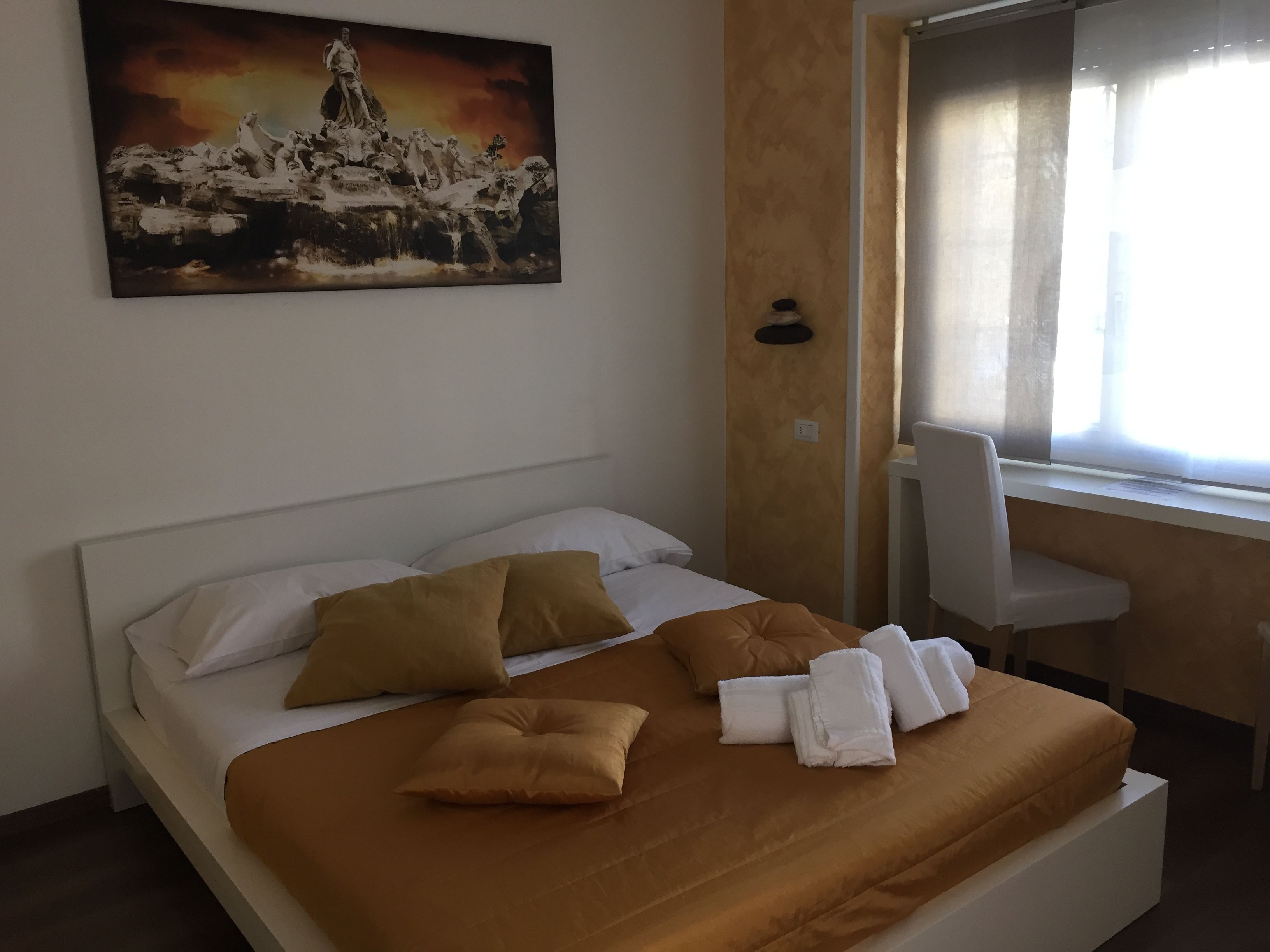 A hotel room with a bed, a desk, and a window.