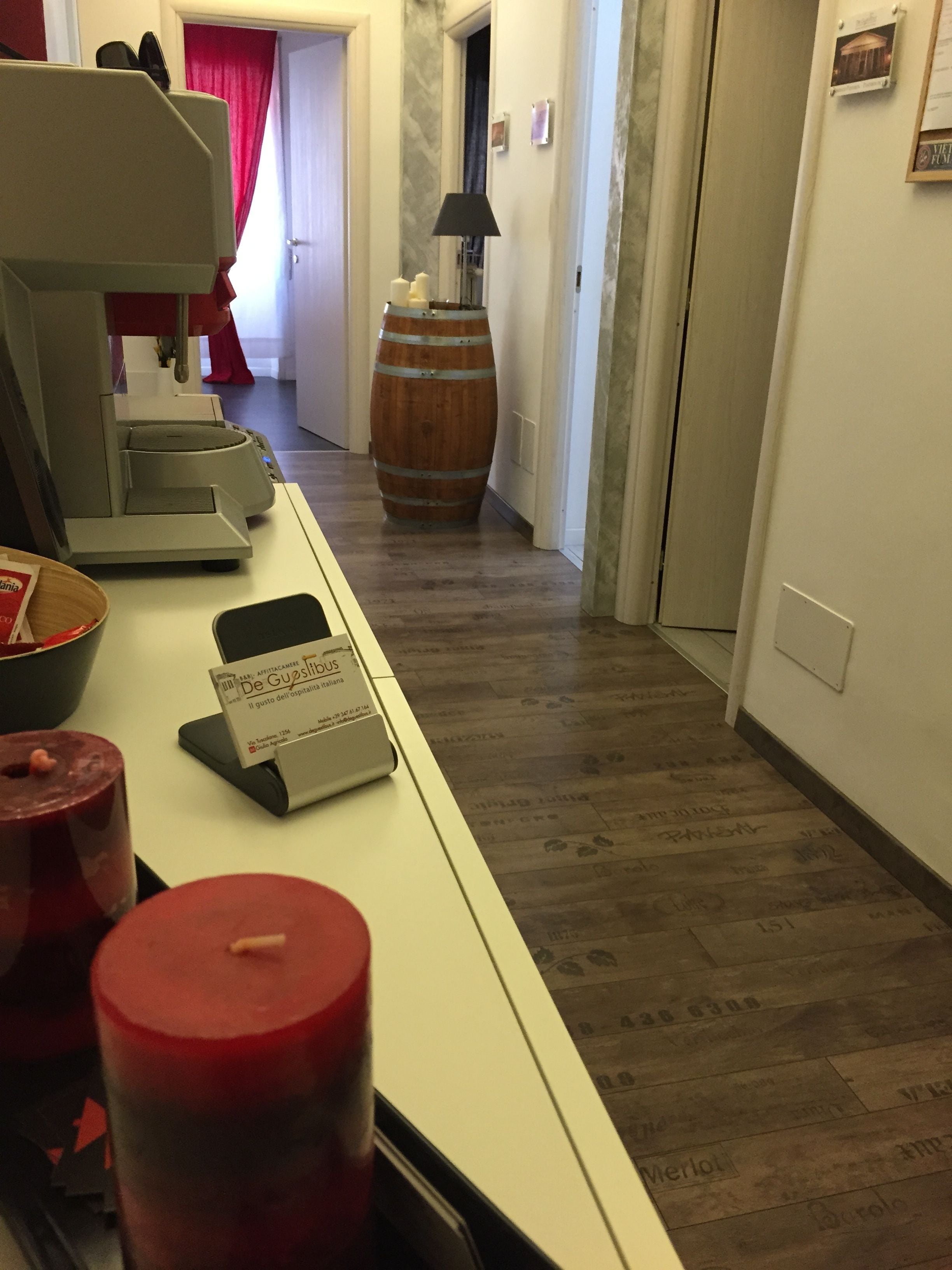 Taulell de recepció d'hotel amb una caixa registradora, un candel vermell i un tonell de fusta al fons.