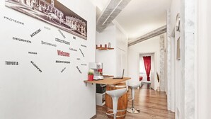 A modern kitchen with a wooden countertop, two white bar stools, and a coffee machine. - De Guestibus (Rome)
