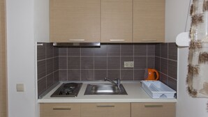 Una cocina con gabinetes de madera, un lavamanos de acero inoxidable, una estufa a gas y una cafetera.