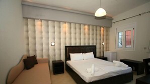 Un dormitorio moderno con una cama grande, un sofá, una mesita de noche y un buró.