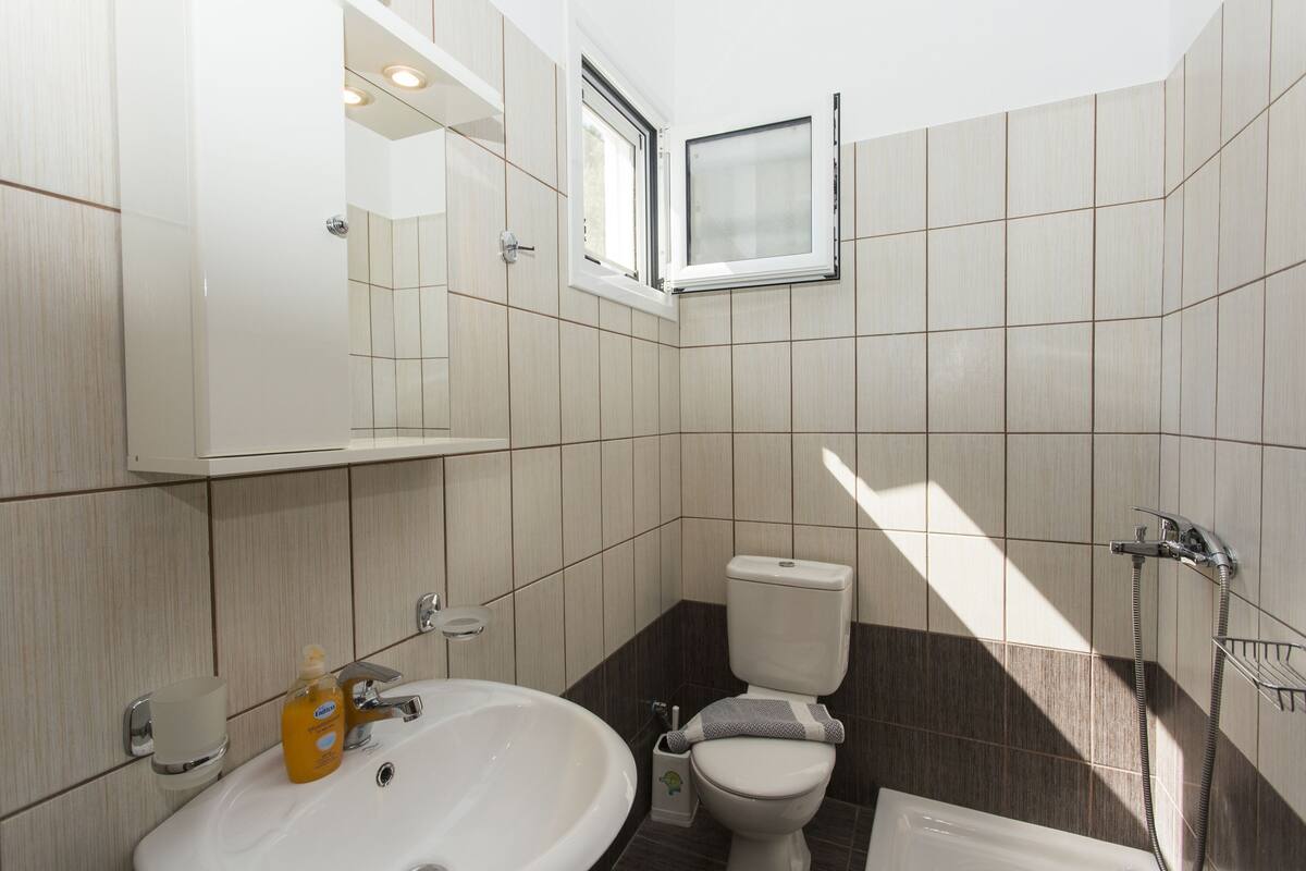 Moderni kylpyhuone, jossa on pesuallas, wc ja kylpyamme.