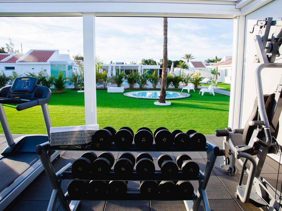 Un gimnasio con cinta de correr, mancuernas y equipamiento para hacer ejercicio.