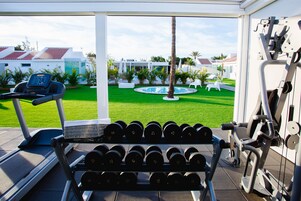 Une salle de sport équipée de tapis de course, d’haltères et d’autres appareils d’exercice.