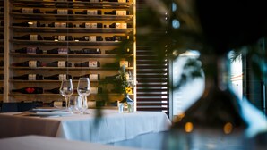 A restaurant with a wine rack, wine glasses, and a table set for dining. - Seven Hotel & Wellness - Caters to Gay Men (San Bartolomé de Tirajana)