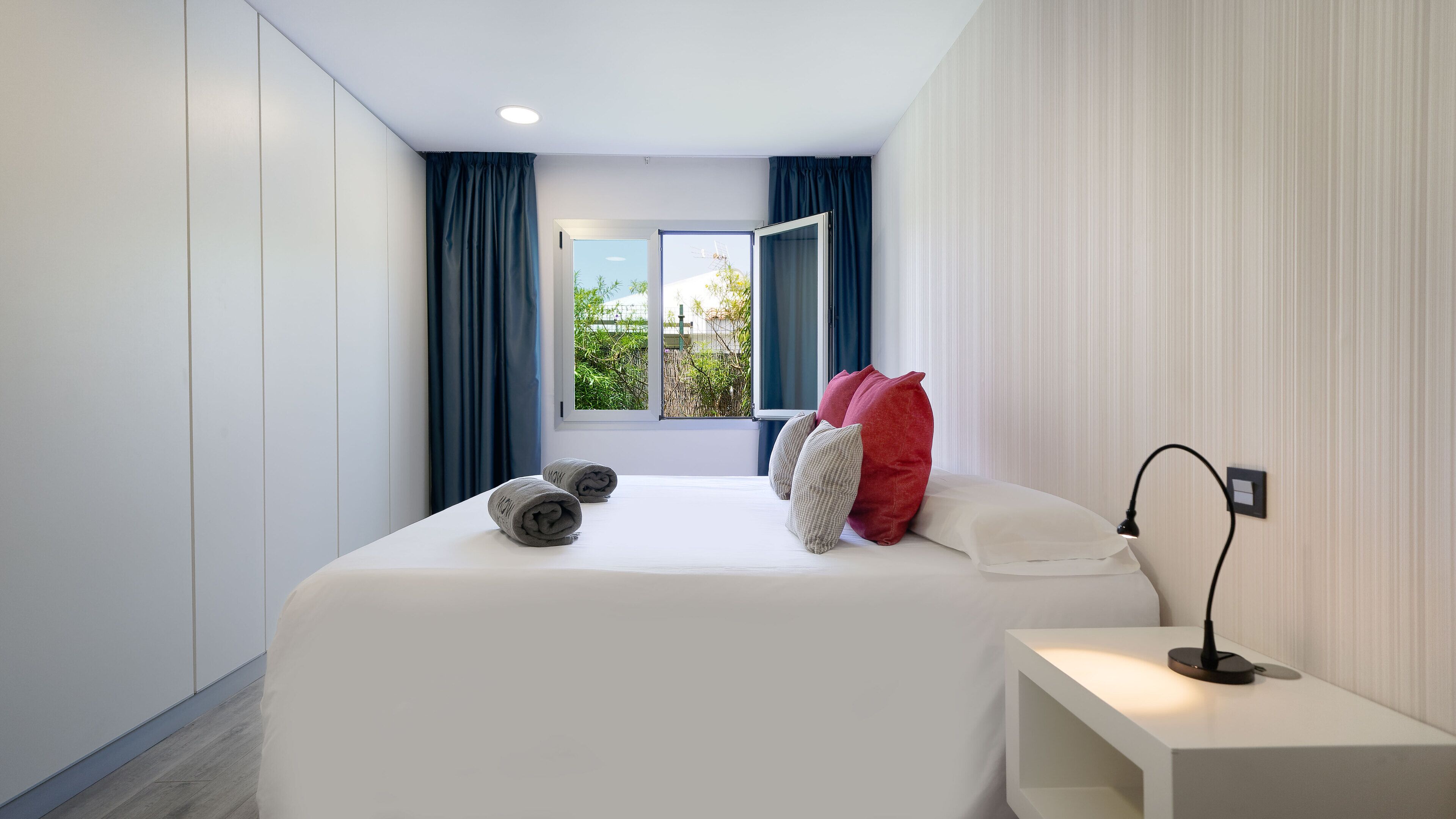 Un dormitorio moderno con una cama grande, una mesita de noche y una ventana con cortinas.