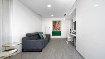 A modern living room with a grey sofa, a small table, and a colorful abstract painting on the wall.