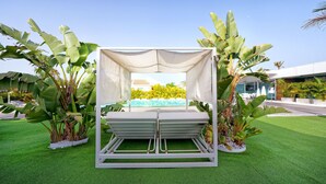 A covered outdoor seating area with a pool view, surrounded by tropical plants. - Seven Hotel & Wellness - Caters to Gay Men (San Bartolomé de Tirajana)