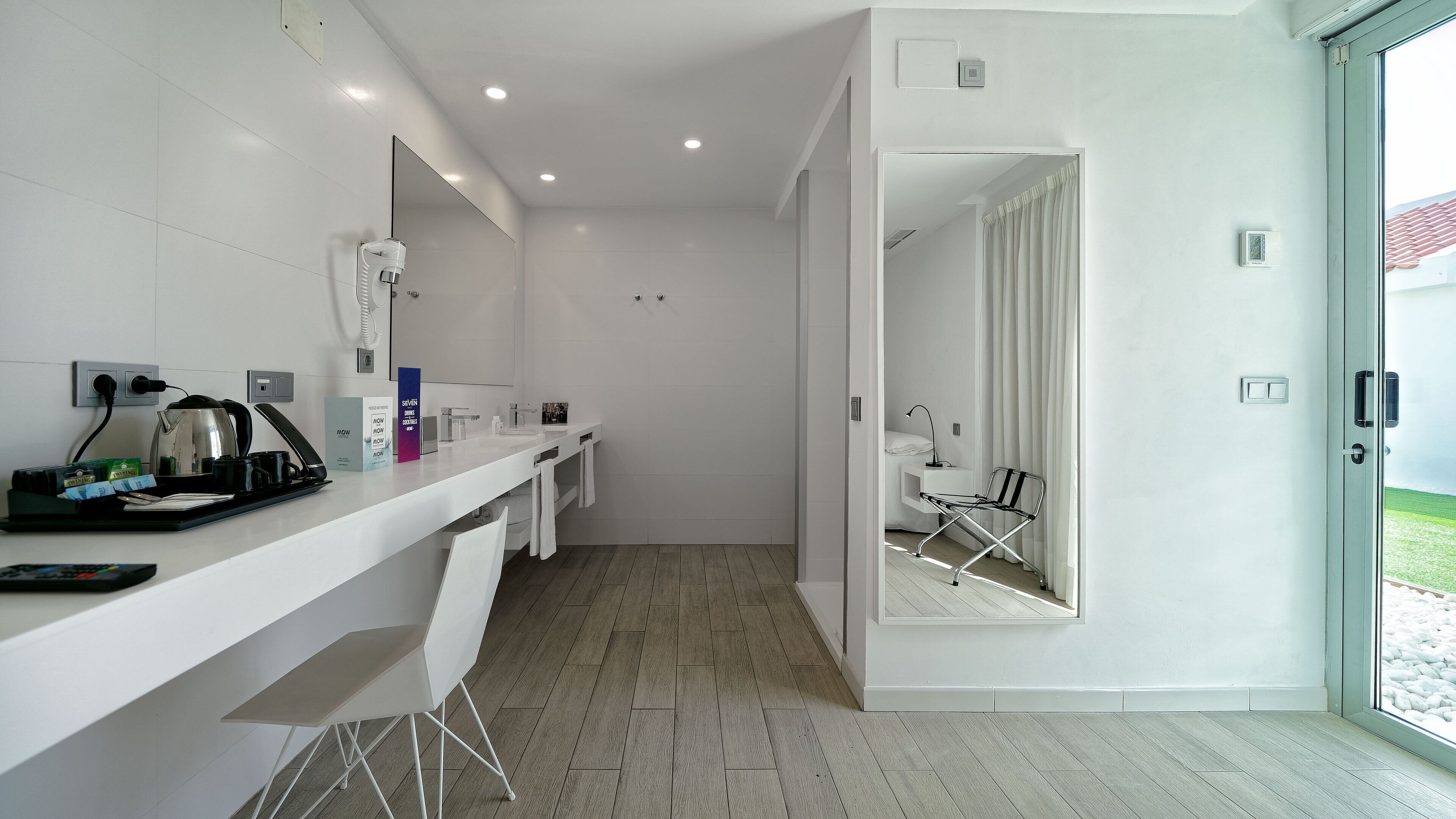 A modern hotel bathroom with a shower, a sink, and a mirror.