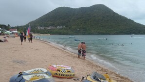 A beach with people, inflatable rafts, and boats on the water. - Stephanie's Apartments Ltd (Gros Islet)