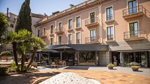 A hotel courtyard with a mosaic fountain, outdoor seating, and a building with balconies. - RVHotels Spa Vila de Caldes (Caldes de Montbui)
