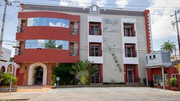 Un hotel con fachada roja y blanca, varios balcones y un cartel grande que dice 'Hotel Suites'.