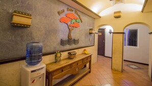 A reception area with a water dispenser, a wooden bench, and a wall-mounted sign reading "Hotel Suites & Residences."