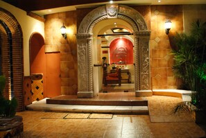 An entrance with a tiled archway, a red wall, and a staircase leading inside. - Hotel Suites Flamboyanes (Mérida)