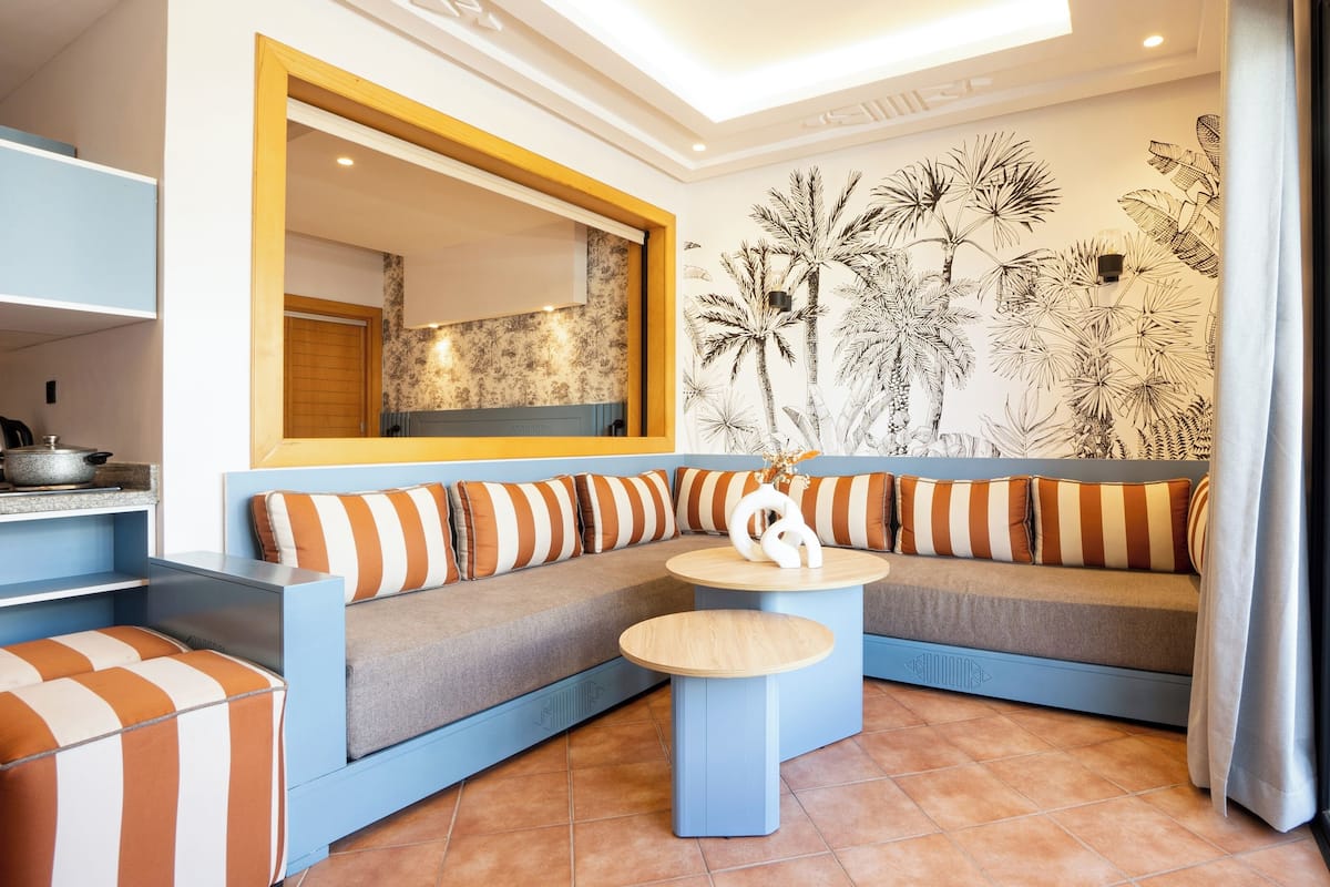 A modern living area with a sofa, a small round table, and a kitchen area with a stove.