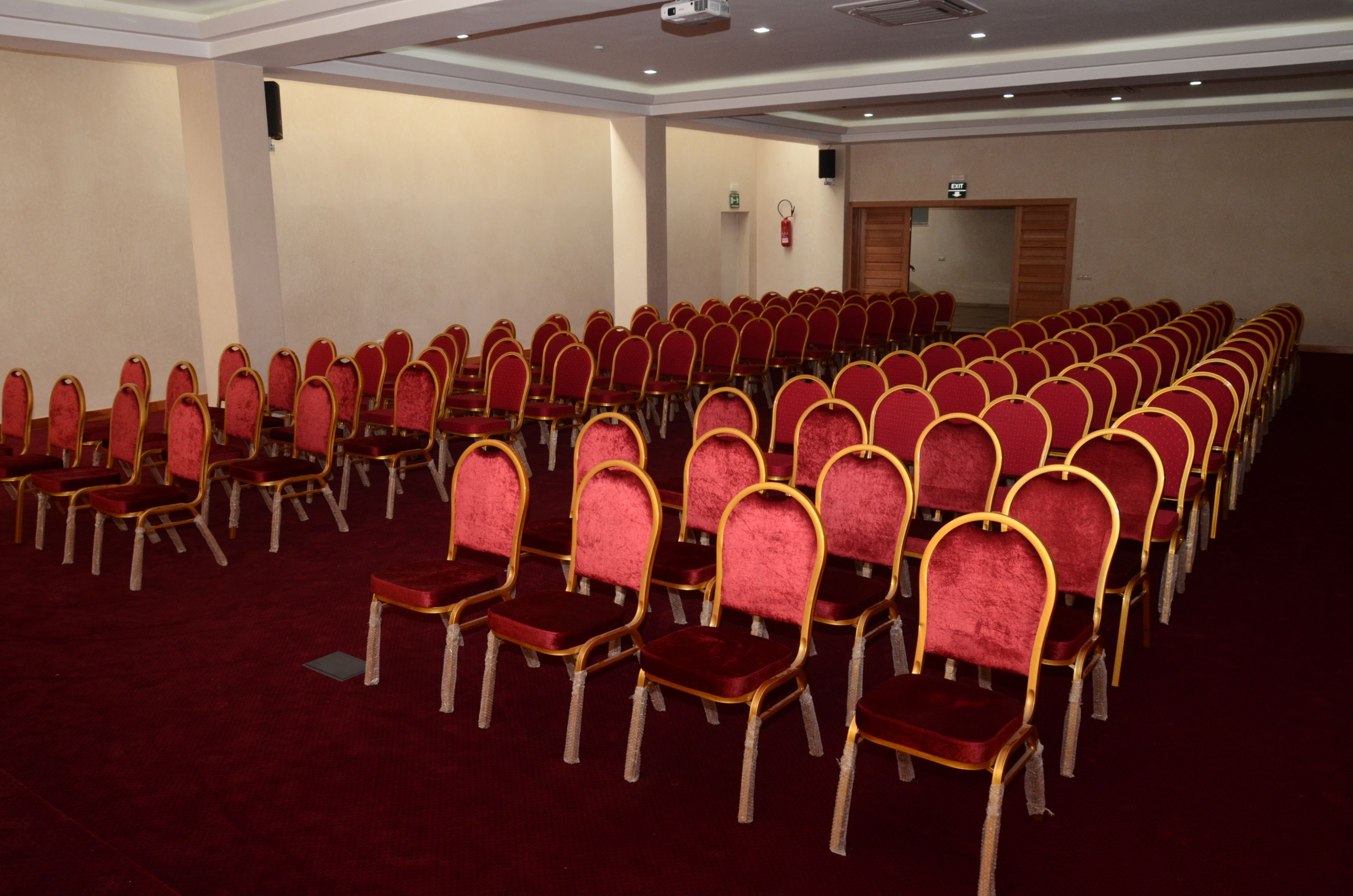 A conference room with rows of red chairs and a carpeted floor.
