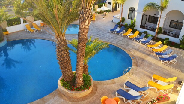 A pool area with lounge chairs and palm trees.