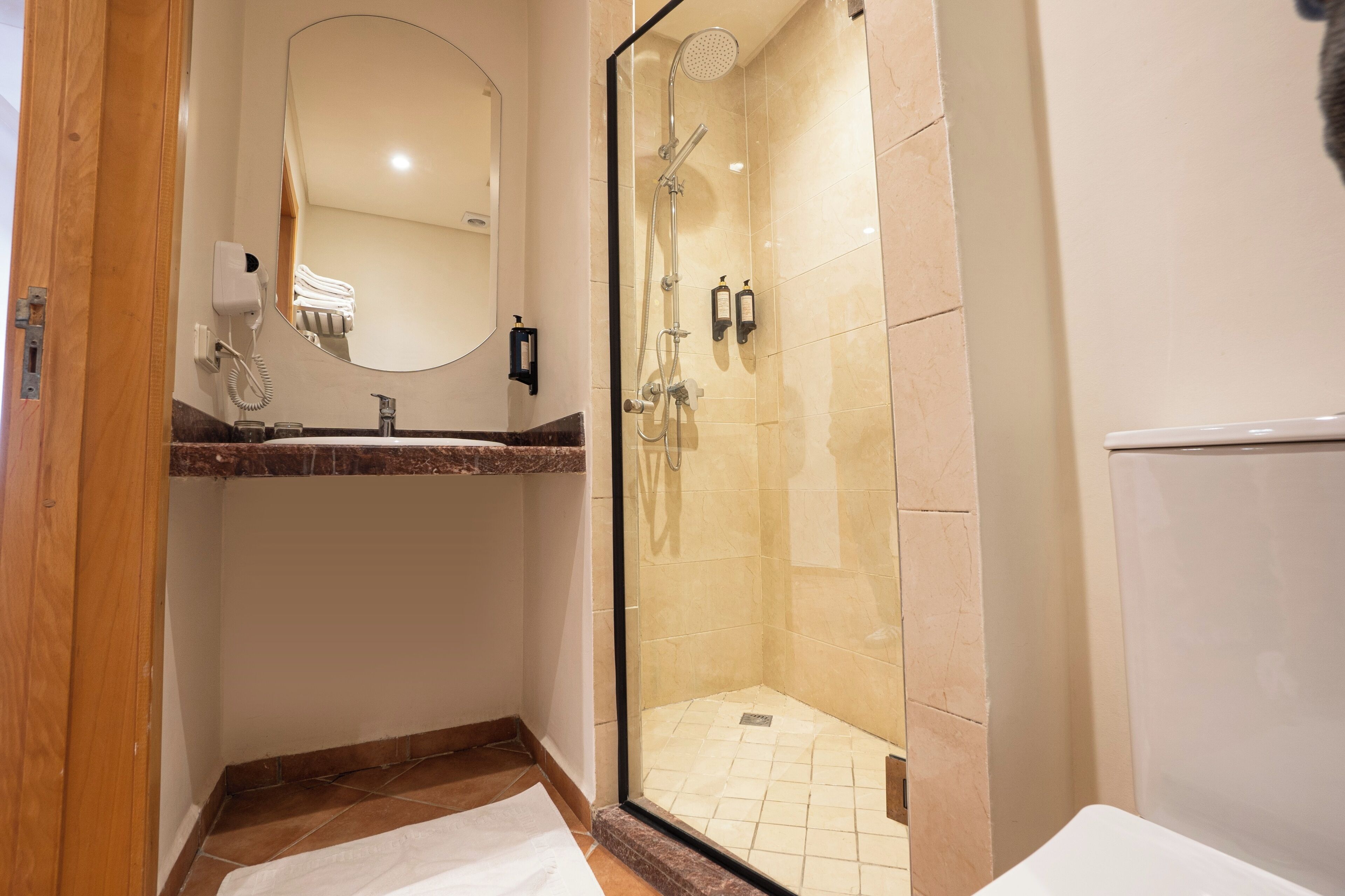 Un bagno moderno con cabina doccia in vetro, lavabo con piano in marmo e specchio.