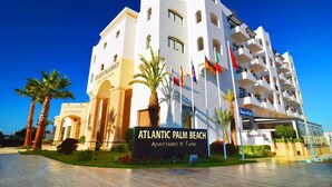 A multi-story hotel named Atlantic Palm Beach with a prominent entrance and flags.