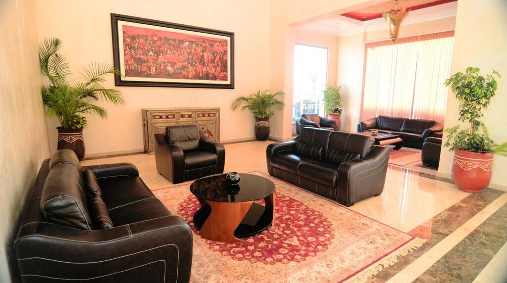 A spacious living room with leather sofas, a coffee table, and potted plants.