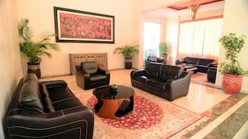 A spacious living room with leather sofas, a coffee table, and potted plants.