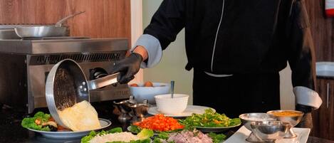 A person preparing food with a pan on a stove, surrounded by various dishes and ingredients.