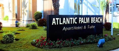 A sign for the Atlantic Palm Beach Apart Hotel & Suite.