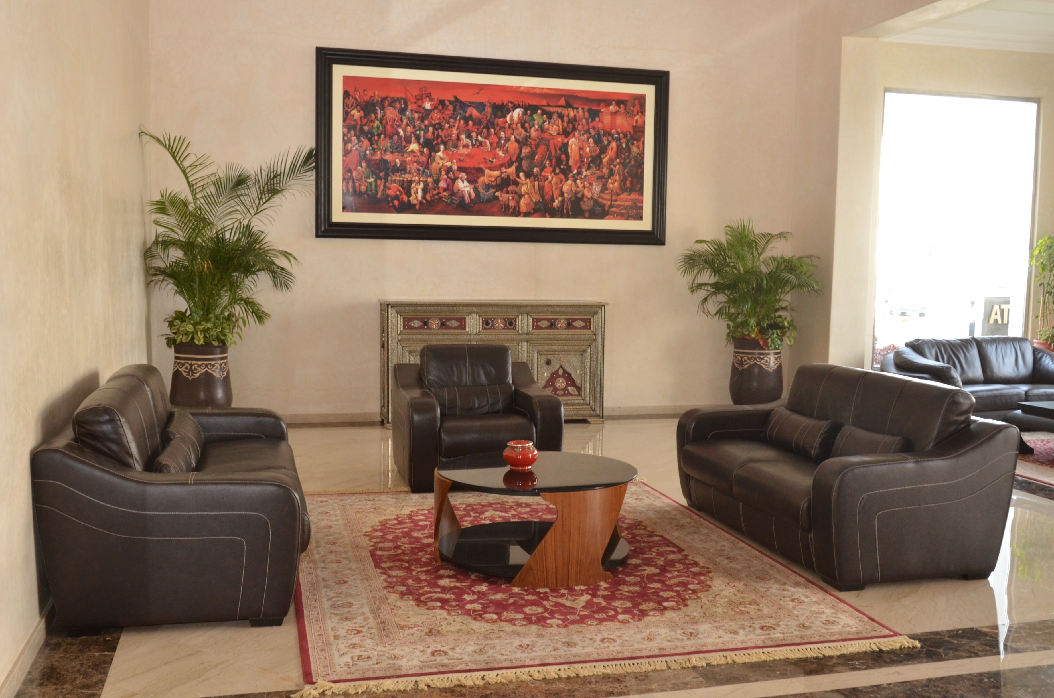 A living room with two leather sofas, a coffee table, a fireplace, and a large framed painting on the wall.
