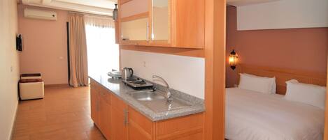 A hotel room with a wooden cabinet, a sink, a bed, and a nightstand.