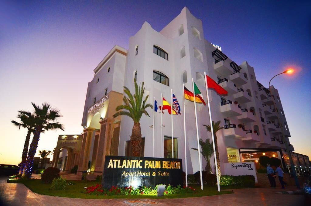Un hôtel à plusieurs étages, sur lequel on peut lire l’inscription suivante : « Atlantic Palm Beach Apart Hotel & Suite ».