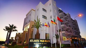 Un hôtel à plusieurs étages, sur lequel on peut lire l’inscription suivante : « Atlantic Palm Beach Apart Hotel & Suite ».