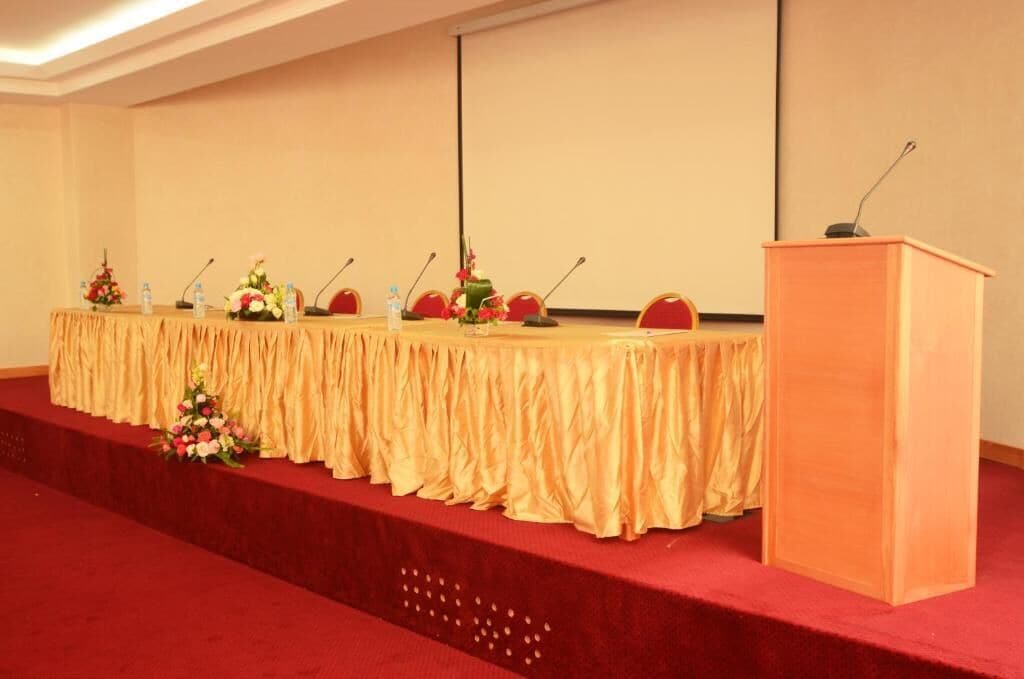 A conference room with a long table, microphones, and a podium.