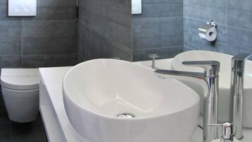 A modern bathroom with a large white sink, a toilet, and a mirror.